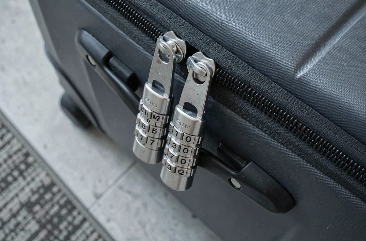 Gros plan sur un cadenas TSA007 fixé aux fermetures éclair d'une valise Samsonite gris anthracite